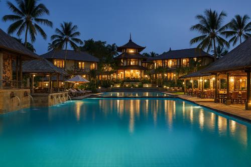 a villa with a swimming pool at night at Mana Suites Bali in Kuta