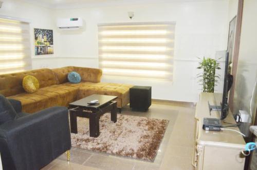 Una sala de estar con un sofá marrón y una mesa. en Living homes enterprise, en Abuja