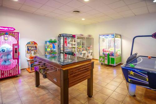 a room with three arcade games and a table at Hotel Servigroup Marina Mar in Mojácar