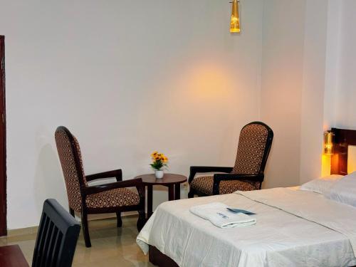 a room with a bed and two chairs and a table at Hotel BKBG in Lomé