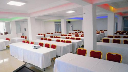 a room with white tables and red chairs at Hotel BKBG in Lomé