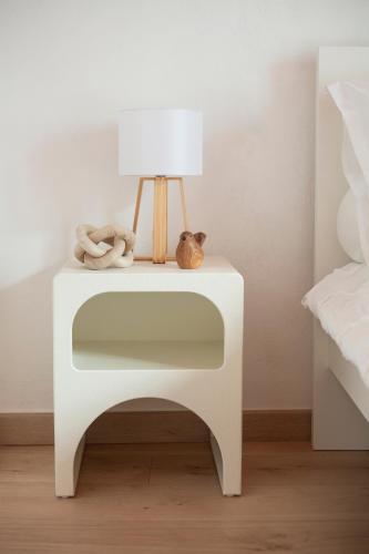 a white bedside table with a lamp and a stuffed animal on it at L'Olivier in Touët-sur-Var
