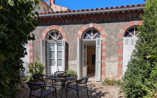a patio with a table and chairs in front of a building at Gîte Wistéria in Mazamet
