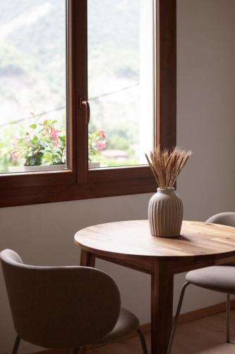 a table with chairs and a vase on it in front of a window at L'Olivier in Touët-sur-Var