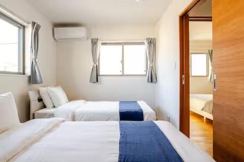 Una habitación de hotel con dos camas y una ventana. en 天の浜Dojo ーThin no Hama Dojoー, en Nanjō