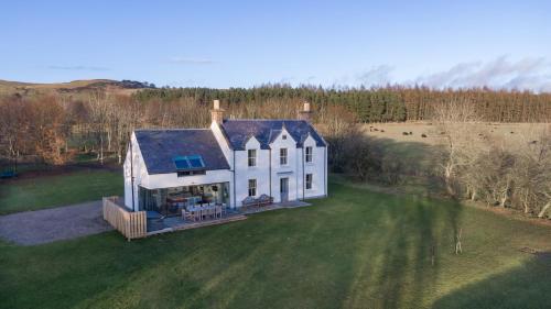 an aerial view of a white house on a green field at Greenmyre Farmhouse with Hot Tub in Kirriemuir