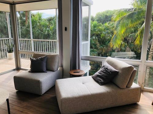 a living room with two chairs and a couch and large windows at Island Beach Club - steps to the Gulf! in Sanibel