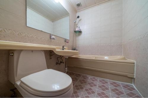 a bathroom with a toilet and a sink and a tub at Taebaek Hotel Sorano in Taebaek