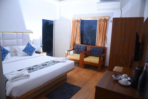 a bedroom with two beds and a chair and a table at Hotel Urban Heaven in Port Blair