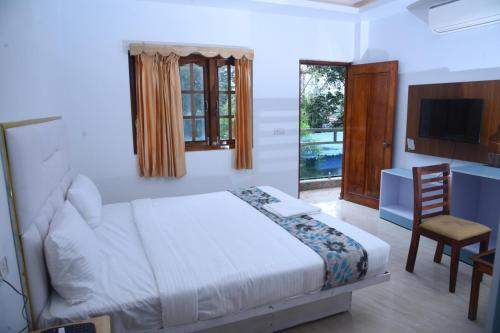 a bedroom with a bed and a desk and a television at Hotel Urban Heaven in Port Blair