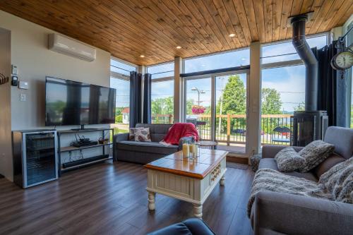 a living room with a couch and a tv and a table at Spa and Outdoor Activities - Le Nano in Saint-Gabriel-de-Brandon