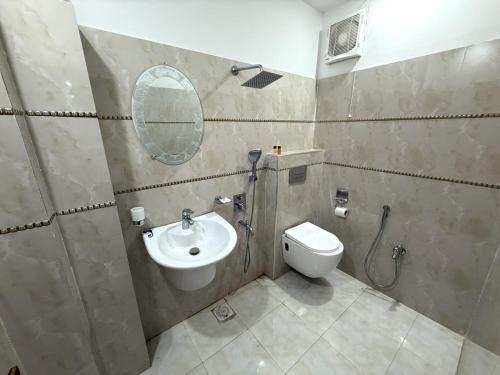 a bathroom with a sink and a toilet and a mirror at Grand Royal Hotel in Lahore