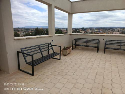 two benches on a balcony with a view of a city at Sweet Berry Apartments-Off Ngong Rd Riruta Nairobi in Nairobi