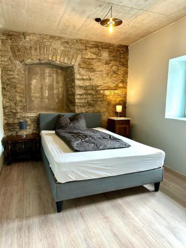 a bedroom with a bed and a stone wall at Backstage, stylische Unterkunft mit Whirlpool in Dahlem