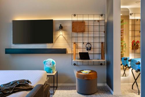 a bedroom with a bed and a tv on a wall at Moxy Berlin Ostbahnhof in Berlin