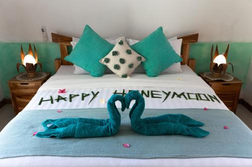 two towel swans are laying on a bed at The New Gili Kolanta Indah in Gili Air