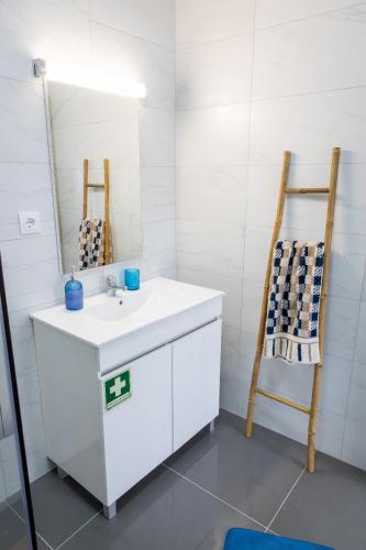 a bathroom with a white sink and a wooden chair at Avó Benta 2 in Faial da Terra