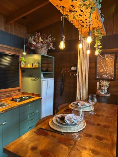 a kitchen with a wooden table with wine glasses on it at Santuá - Cabana Bellagio in Rio dos Cedros
