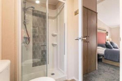 1 dormitorio y baño con ducha y aseo. en Primrose Lodge with Hot Tub, en York
