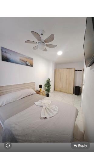 a bedroom with a white bed with a ceiling fan at Pensiòn Cerdà 112 in Alicante