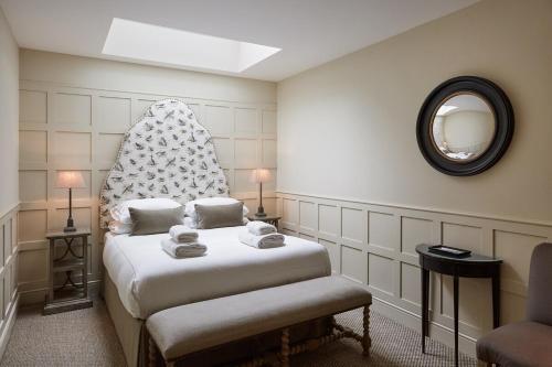 ein Schlafzimmer mit einem Bett mit einem Stuhl und einem Spiegel in der Unterkunft Grey's Court Cottages in Southrop