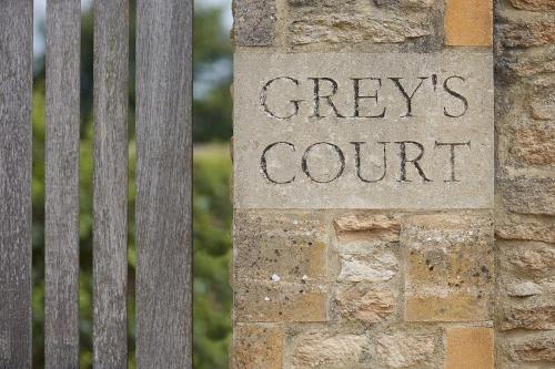 eine Bank auf einer Mauer mit den Worten Creep Courts Court in der Unterkunft Grey's Court Cottages in Southrop