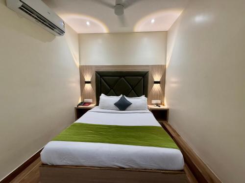 a bedroom with a bed with green sheets and lamps at Hotel Riza - Near Nesco Exhibition Centre in Mumbai