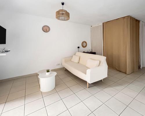 a living room with a white couch and a table at Studio clim cosy avec piscine & terrasse in La Roquette-sur-Siagne