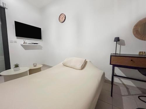 a white bedroom with a bed and a tv at Studio clim cosy avec piscine & terrasse in La Roquette-sur-Siagne