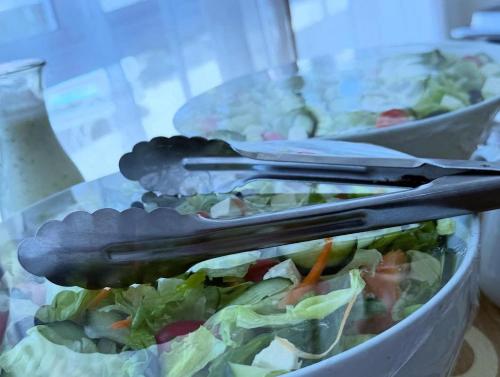 two bowls of salad with tongs on top of it at Sapphire Hotel Halevy Heritage in Bloemfontein