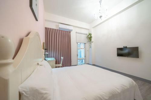 a white bedroom with a bed and a tv at 花蓮發現民宿-無人民宿自助入住-包棟可烤肉可麻將 in Hualien City
