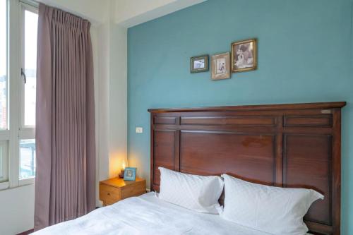 a bedroom with a bed with a wooden headboard and a window at 花蓮發現民宿-無人民宿自助入住-包棟可烤肉可麻將 in Hualien City