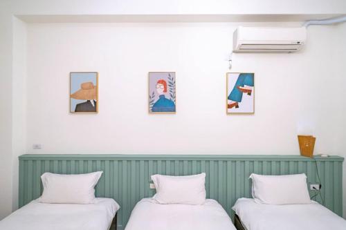 two beds in a room with pictures on the wall at 花蓮發現民宿-無人民宿自助入住-包棟可烤肉可麻將 in Hualien City
