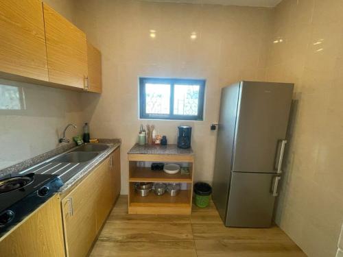 una pequeña cocina con nevera de acero inoxidable en Forever Appartements Cosy, en Cotonou