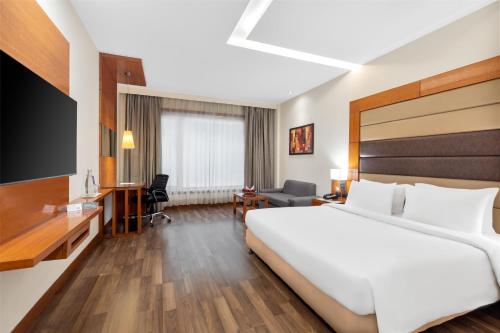 a hotel room with a large bed and a tv at Country Inn & Suites by Radisson, Gurugram Sector 12 in Gurgaon