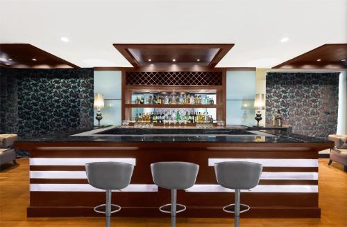a bar in a hotel with three bar stools at Country Inn & Suites by Radisson, Gurugram Sector 12 in Gurgaon