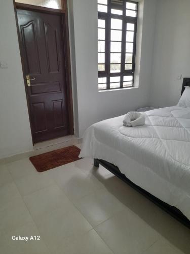 a bedroom with a bed and a window and a door at Mugo Queen's Stay in Lotus Island