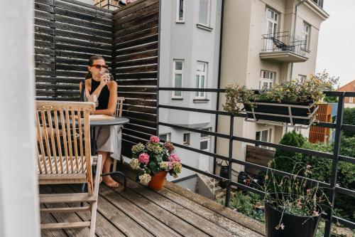 a woman sitting at a table on a balcony at Bed&Breakfast & Apartment Klafé in Brno