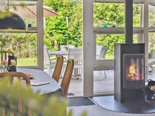 a fireplace in a dining room with a table and chairs at Holiday Home Batsha - 350m from the sea by Interhome in Tisvildeleje