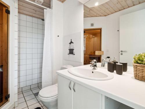 a white bathroom with a toilet and a sink at Holiday Home Greta - 200m from the sea by Interhome in Vester Sømarken