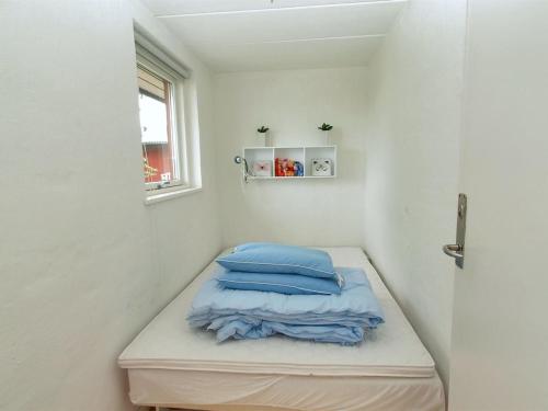 a small room with a bed with blue pillows at Apartment Magnus - 6km from the sea by Interhome in Åkirkeby