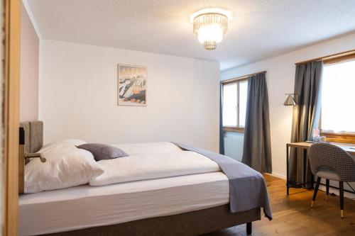 a bedroom with a bed and a desk and a window at La Tgoma - Hotel & Restaurant in Lenz