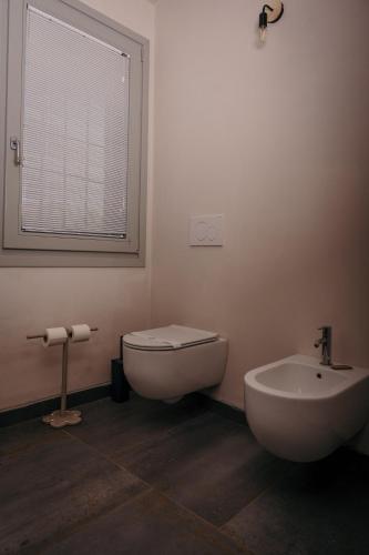 a bathroom with a toilet and a sink and a window at Agriturismo Albero del Latte in Bagnolo San Vito
