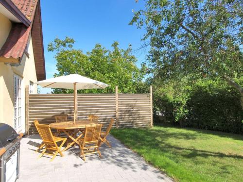 a table and chairs with an umbrella on a patio at Holiday Home Ødmar - 400m from the sea by Interhome in Neksø