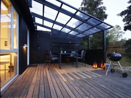 eine Pergola auf einer Terrasse mit einem Tisch und einem Grill in der Unterkunft Holiday Home Talvikki - 250m from the sea by Interhome in Neksø