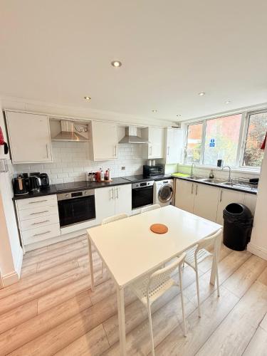 a kitchen with a white table and a white counter top at 15 min to Central London Guest Suites 22 in London