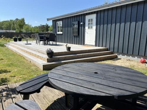a wooden picnic table on a deck with a house at Holiday Home Algeth - 350m from the sea by Interhome in Neksø