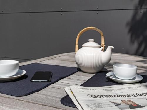 a tea pot and two cups and a newspaper on a table at Holiday Home Muriel - 150m from the sea by Interhome in Neksø