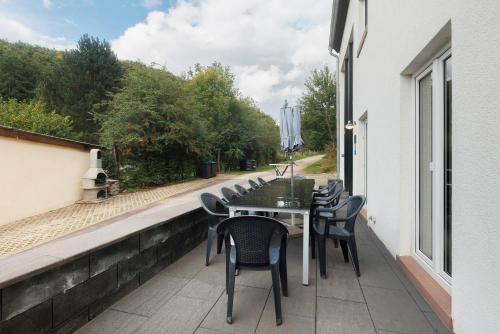 a patio with a table and chairs on a balcony at Ferienhaus Eifel Atrium in Zweifelscheid
