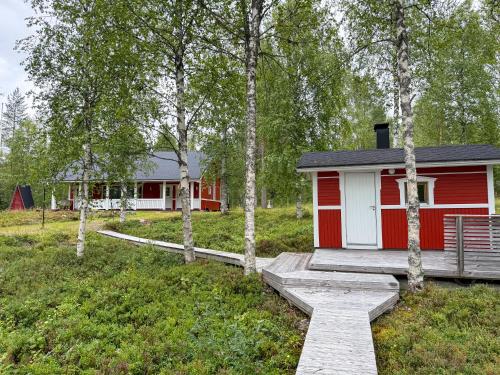 una cabaña roja y blanca en un campo con árboles en Northern Lights Lakehouse, en Rovaniemi